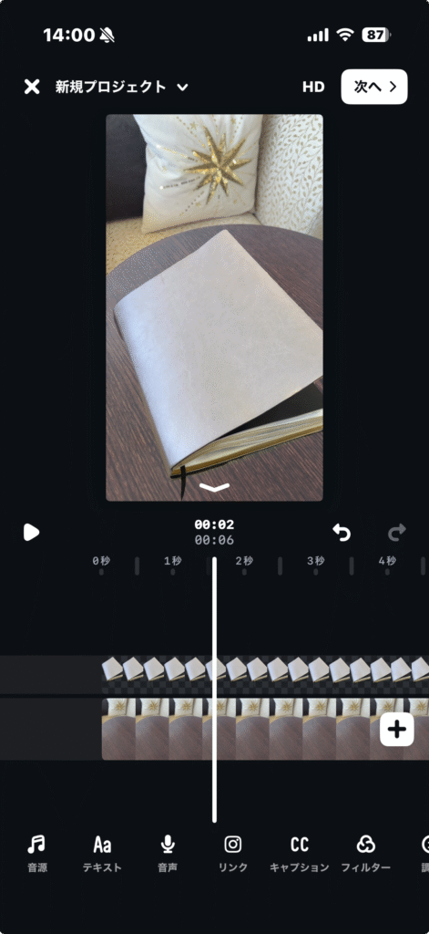 Editsアプリの編集画面。手帳の映像をAIで背景削除した。2本のクリップがタイムラインに重ねられており、動画の差し替え・追加の状態を示している。プレビュー画面には手帳と背景のクッションが映っている